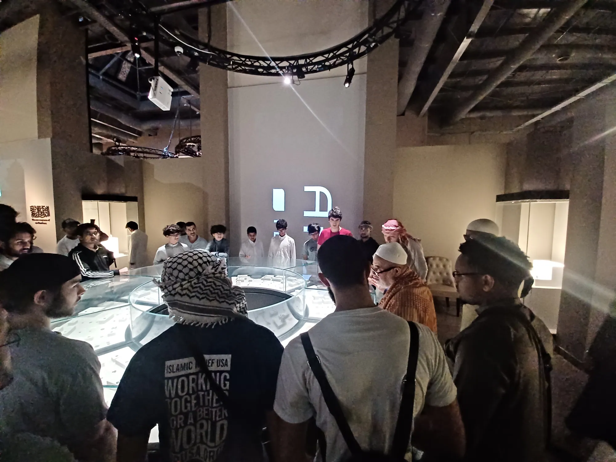 Students leaning in to examine an ancient coin during a guided museum visit in Jeddah.